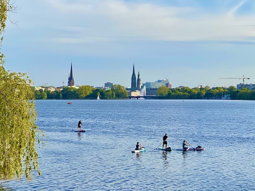 Stehpaddler von dem typischen Hamburg Panorama: SUP auf der Alster ist im Sommer für Einwohner und Besucher ein spannender Zeitvertreib. Foto: Sascha Tegtmeyer