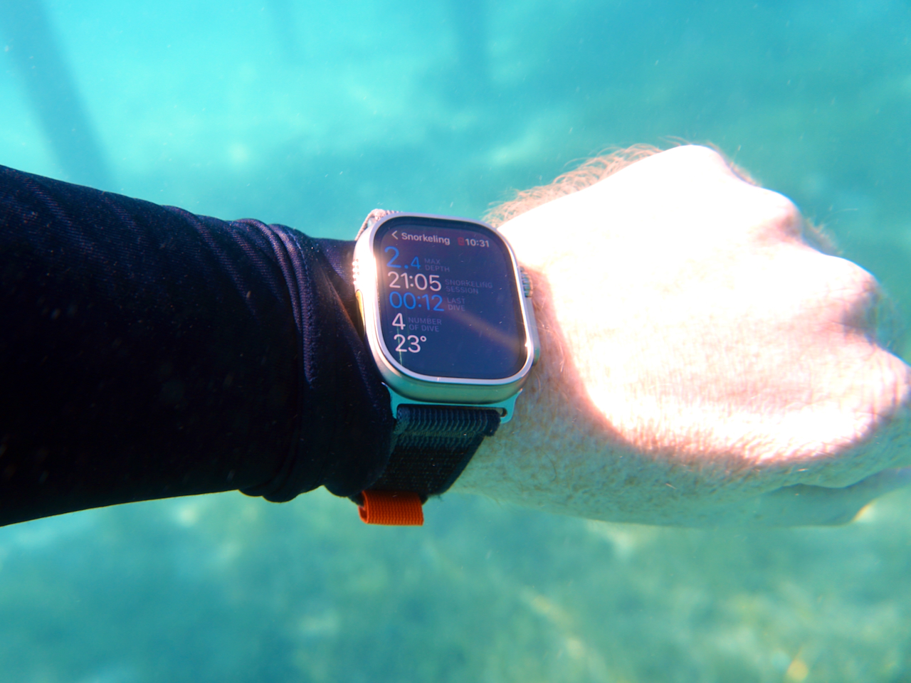Auf dem Bild sieht man eine Apple Watch Ultra, die beim Schnorcheln unter Wasser gehalten wird. Im Hintergrund sieht man den Meeresgrund. Ich war auch schon mit dem Apple Watch Trail Loop schnorcheln und tauchen. Foto: Sascha Tegtmeyer Apple Watch Trail Loop Test Erfahrungen Testbericht Erfahrungsbericht „Trail Loop. Komfort für lange Läufe. Besonders dünn, leicht und flexibel. Und mit einem einfachen Schlaufen­verschluss, damit du es beim Training schnell anpassen kannst. Das Gewebe ist besonders dehnbar und kann für die perfekte Passform einfach angezogen werden.“ 