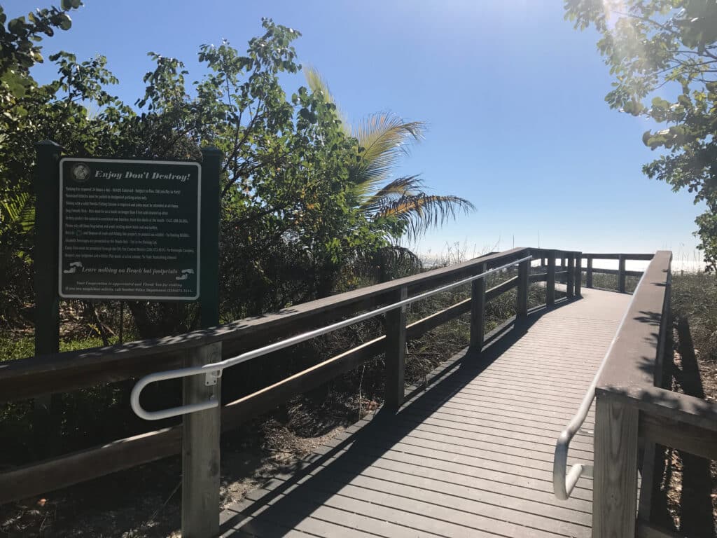 Holzsteg zum Strand auf Sanibel Island zwischen Palmen und Küstenpflanzen